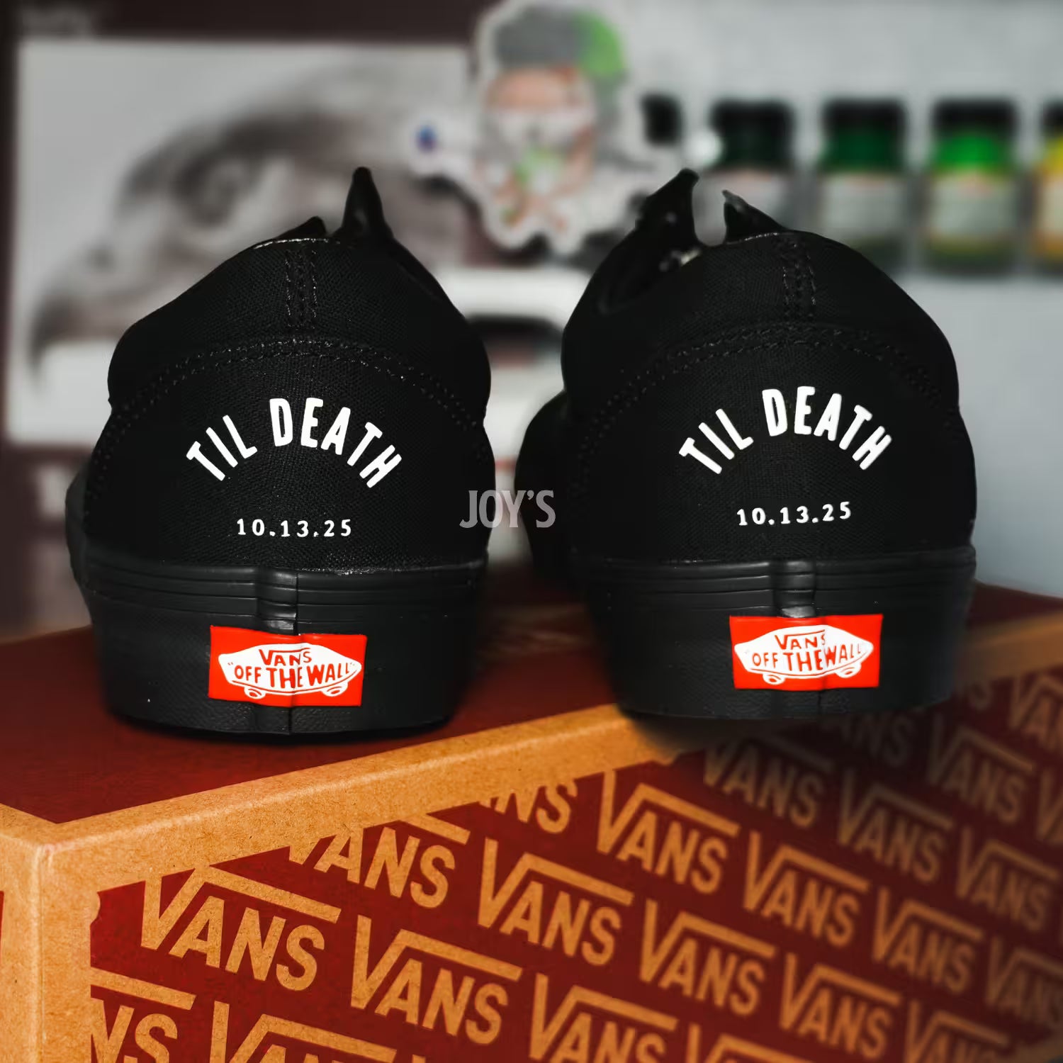 Black Vans custom wedding sneakers with “Til Death” text and wedding date printed on the heels, shown in a rear view on a Vans shoebox