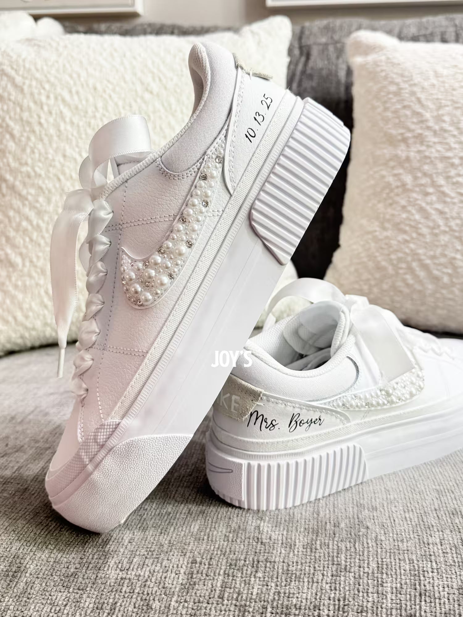 White custom wedding sneakers with pearl and rhinestone embellished swoosh, satin ribbon laces, and personalized bride name and wedding date on the heel