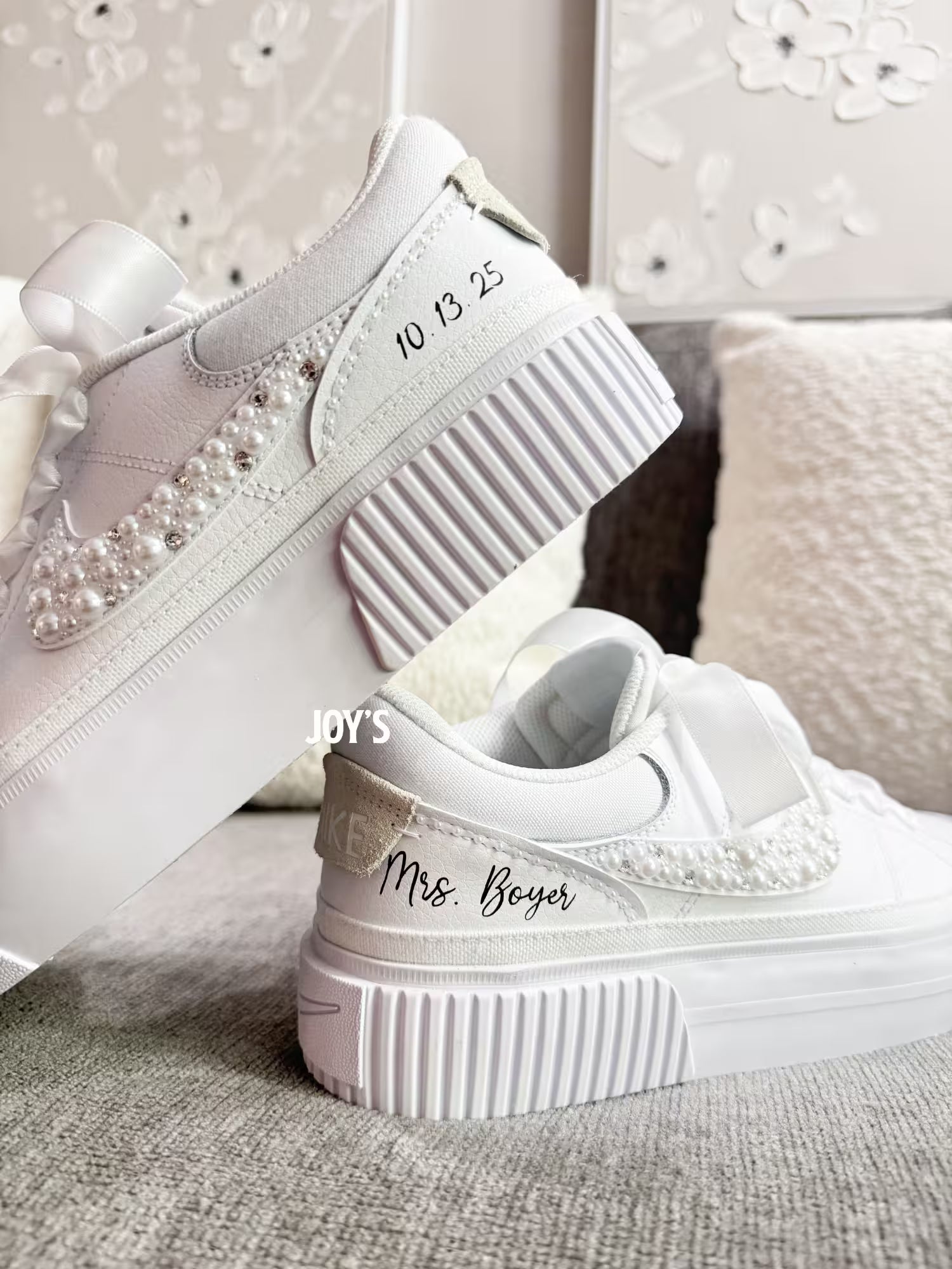 White custom wedding sneakers with pearl and rhinestone embellished swoosh, satin ribbon laces, and personalized bride name and wedding date on the heel