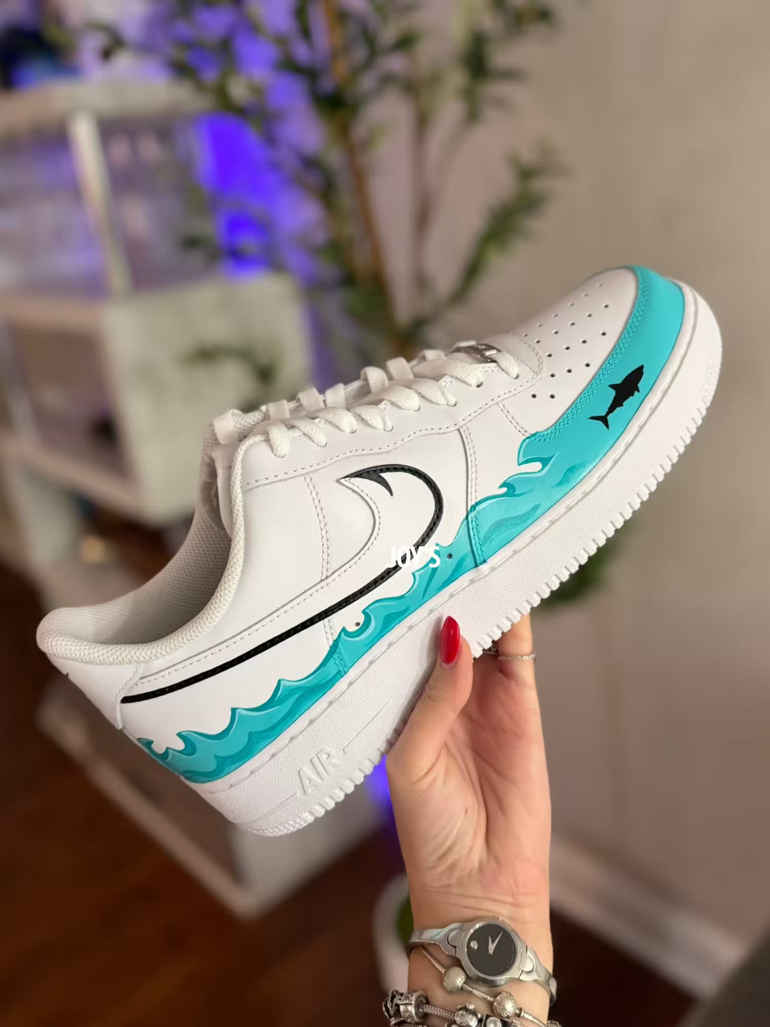 White custom Nike Air Force 1 sneakers with teal sea wave inspired hand-painted details and black swoosh with a shark figure