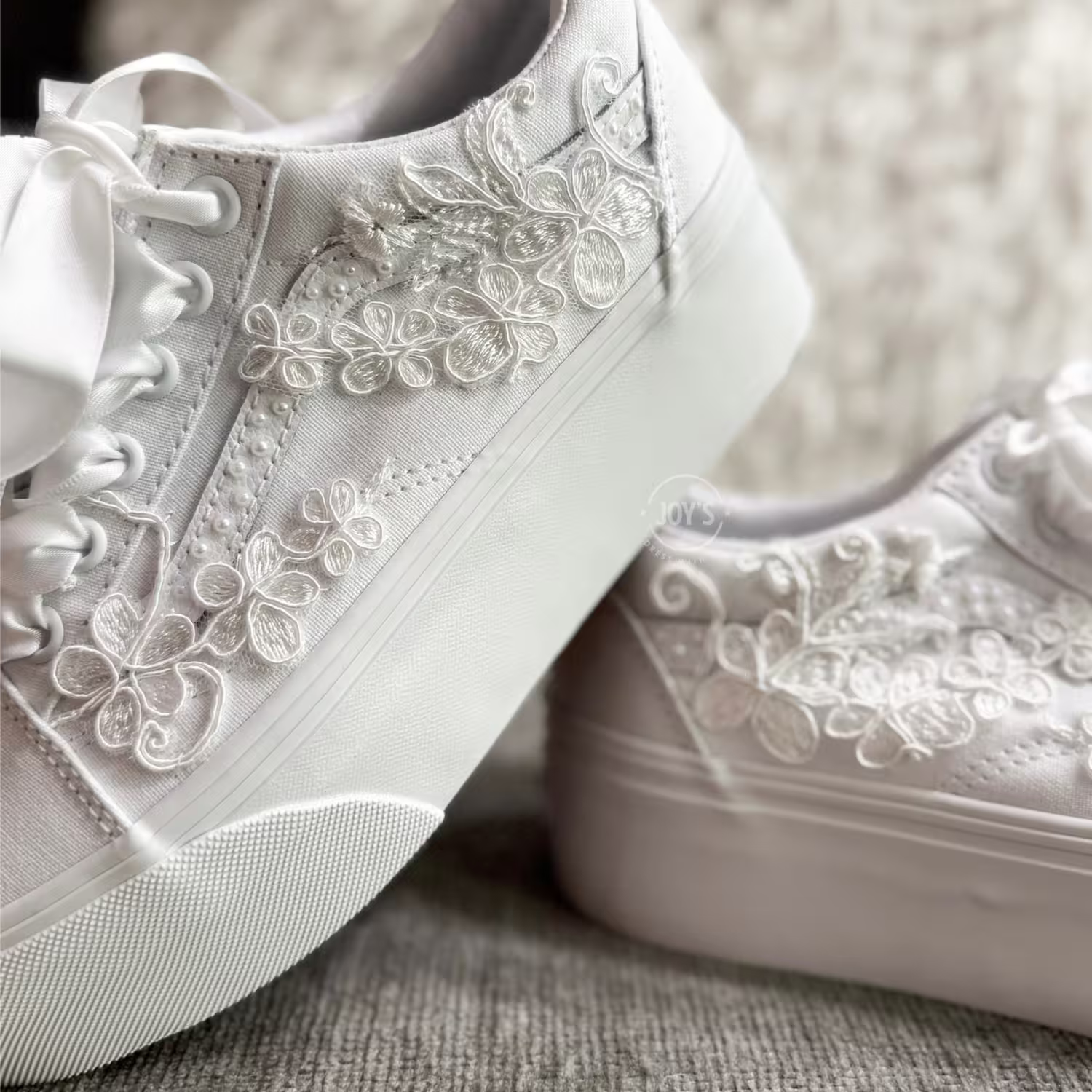 White platform Vans wedding sneakers with lace floral appliqués, pearl detailing, and satin ribbon laces, shown in a close-up side view