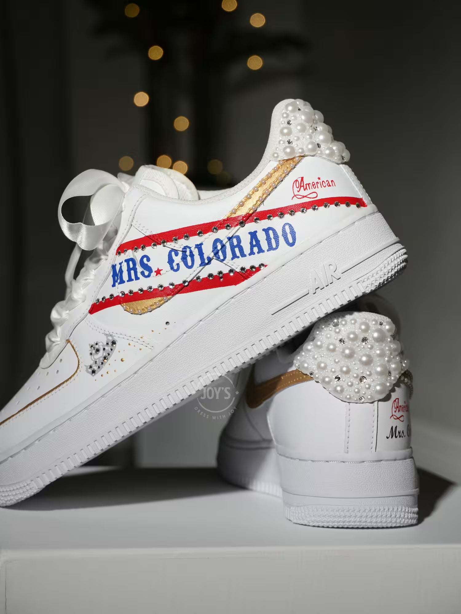White custom wedding sneakers with pearl-embellished heel, rhinestone details, red and blue painted accents, and personalized “Mrs. Colorado” text on the side, shown in a close-up side view