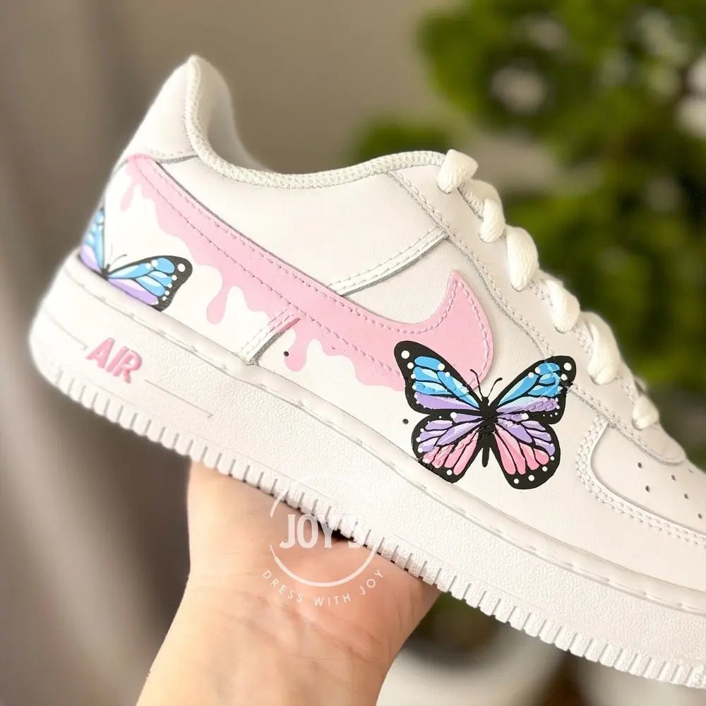Custom hand-painted Nike Air Force 1 Low sneakers with pastel butterfly artwork and pink swoosh details.