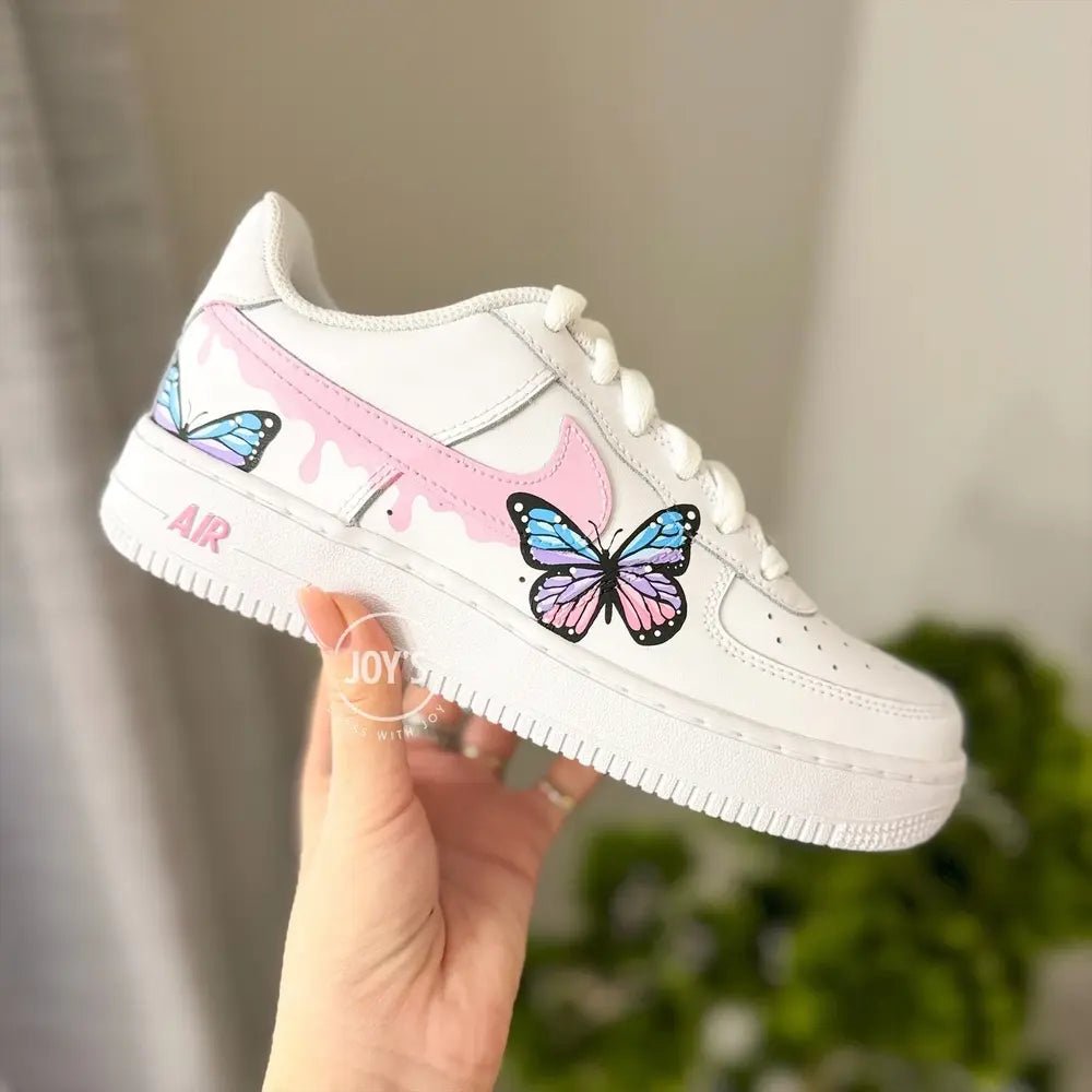 Custom hand-painted Nike Air Force 1 Low sneakers with pastel butterfly artwork and pink swoosh details.