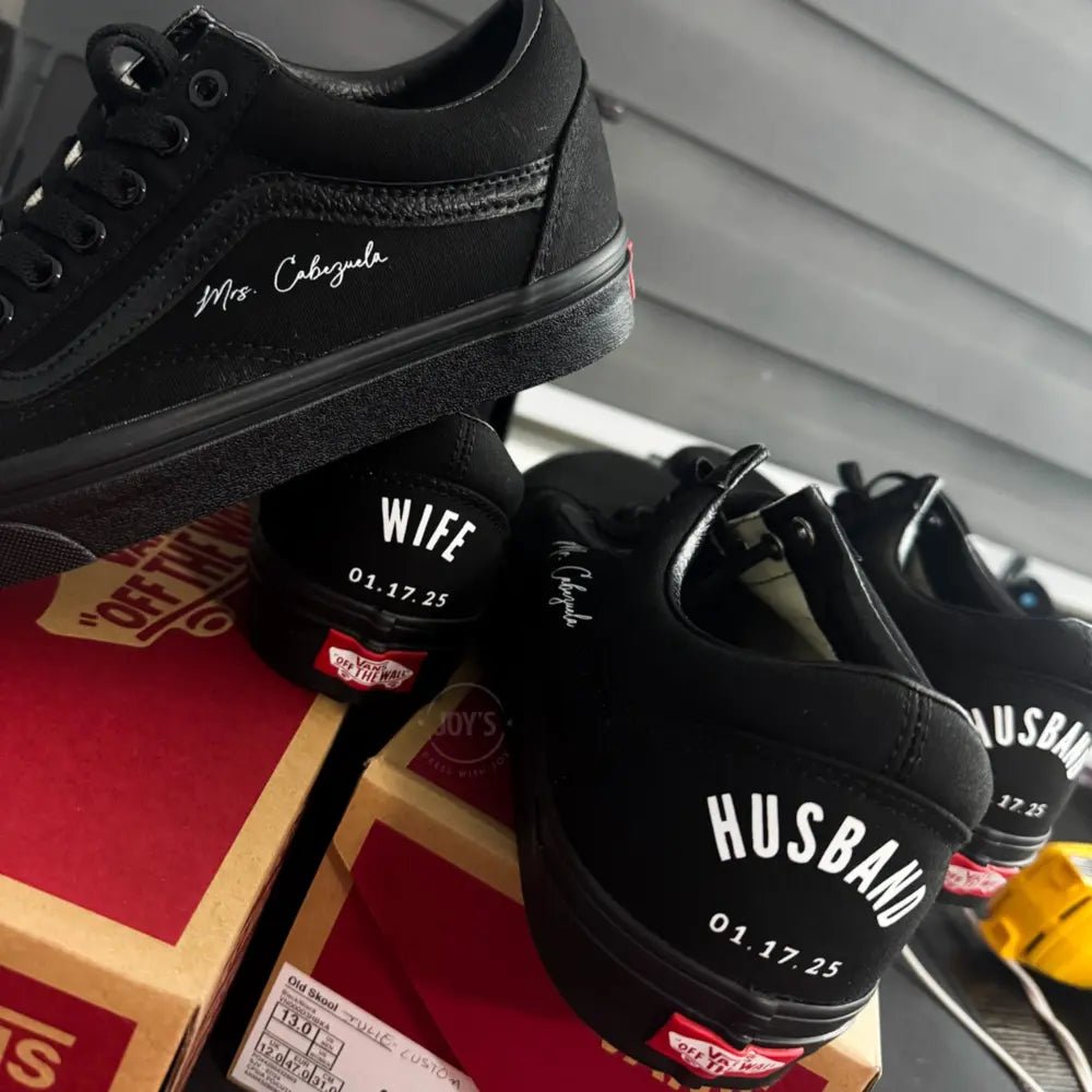 Black Vans custom wedding sneakers with “Husband and wedding date printed on the heels, shown in a rear view on a Vans shoebox