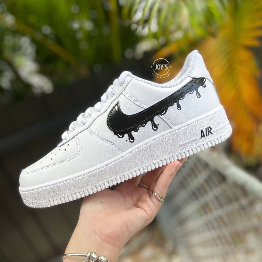 White Nike Air Force 1 with black dripping swoosh detail, shown from the side.