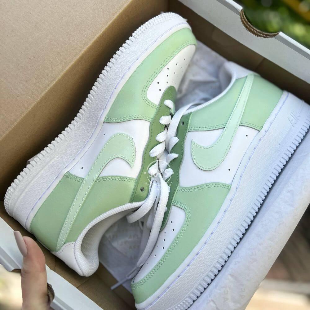 White Nike Air Force 1 low-top sneakers with soft mint green panels and swoosh