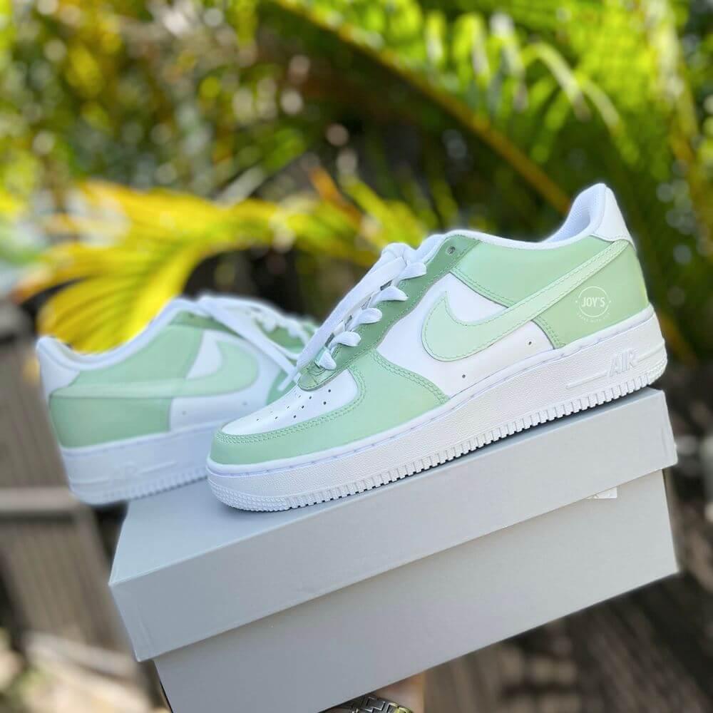 White Nike Air Force 1 low-top sneakers with soft mint green panels and swoosh