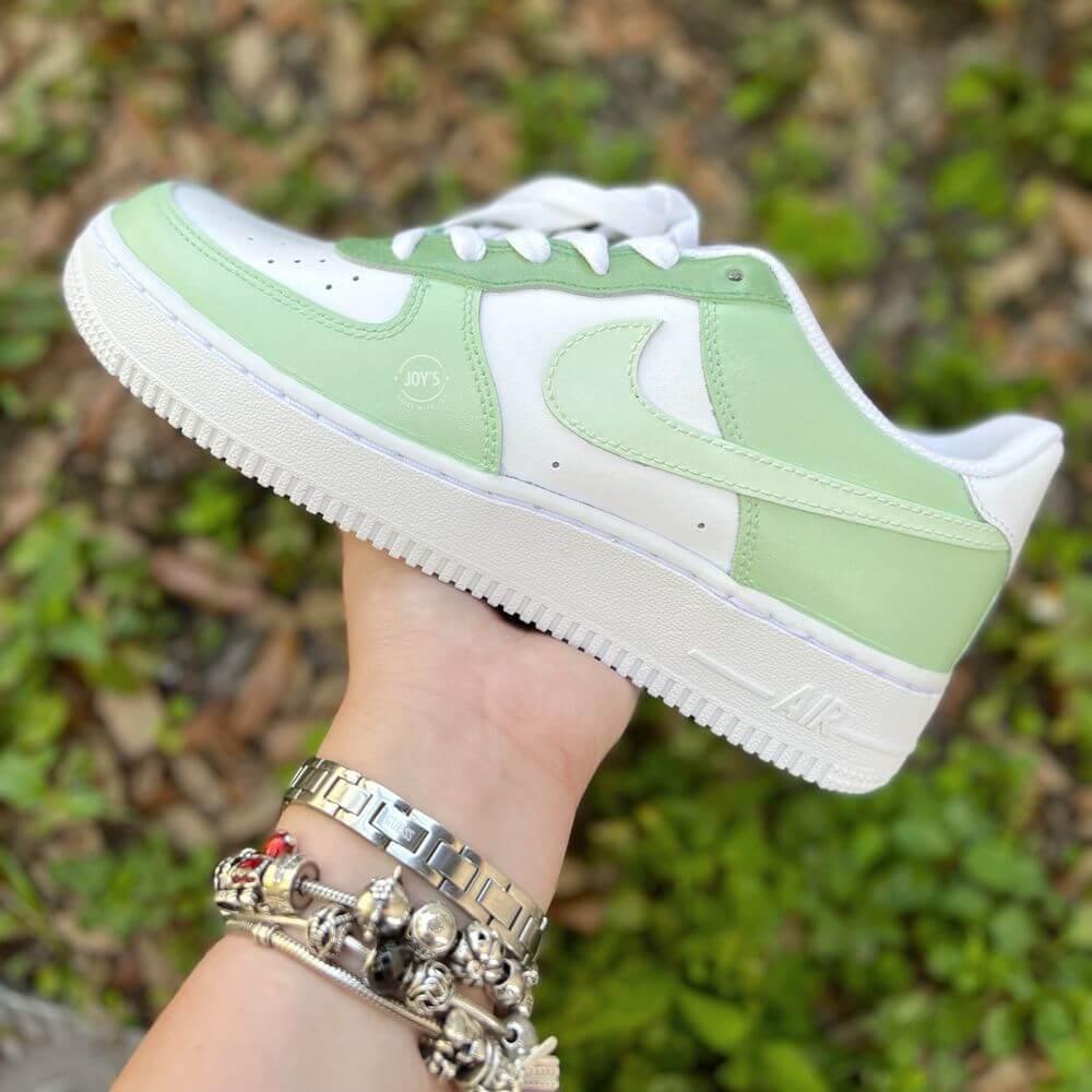 White Nike Air Force 1 low-top sneakers with soft mint green panels and swoosh
