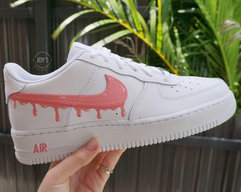 White Nike Air Force 1 sneakers with coral pink dripping swoosh design