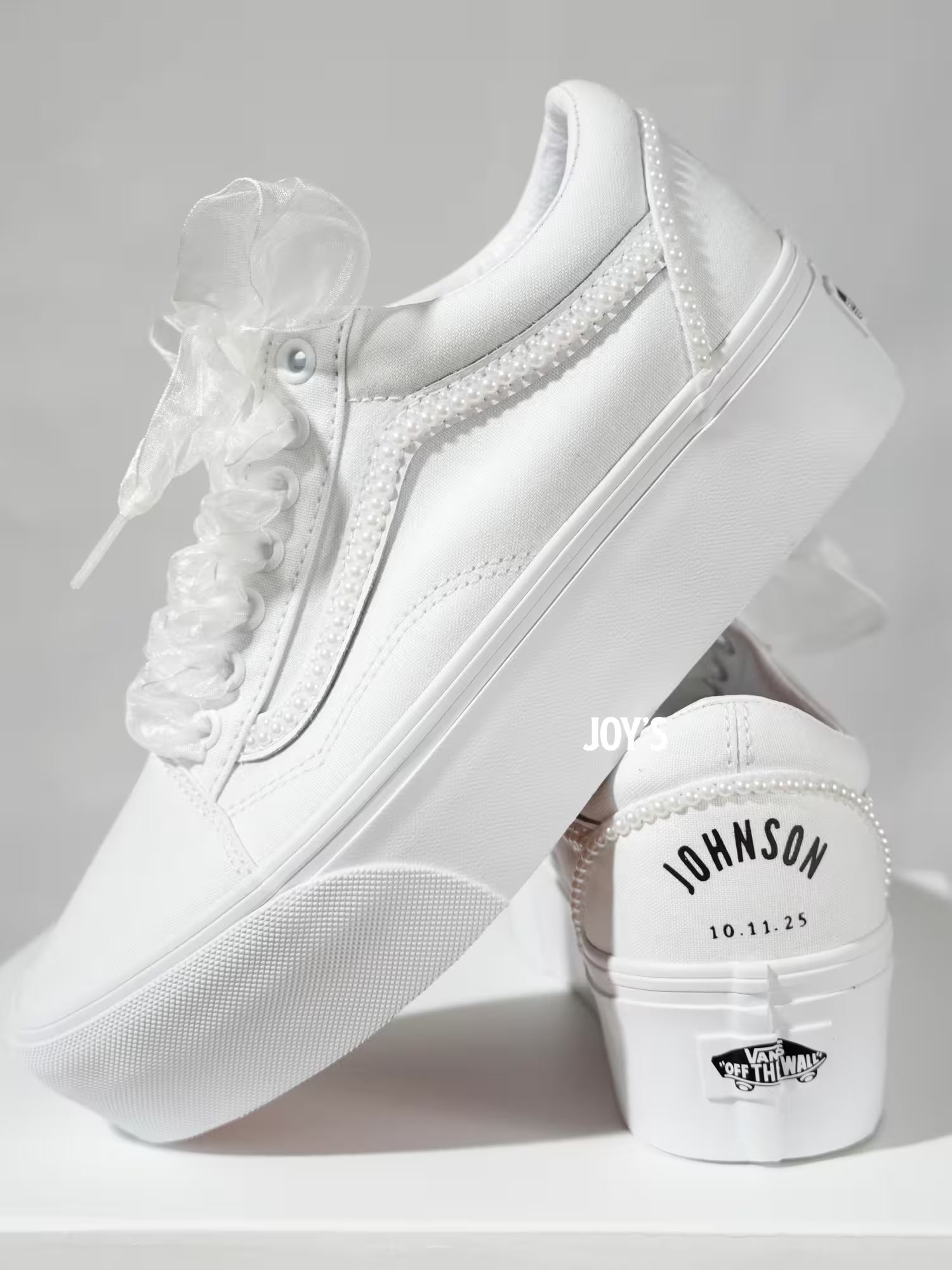White platform Vans wedding sneakers with pearl trim, satin ribbon laces, and personalized “Mrs.” and last name with wedding date printed on the heels, shown in a rear view