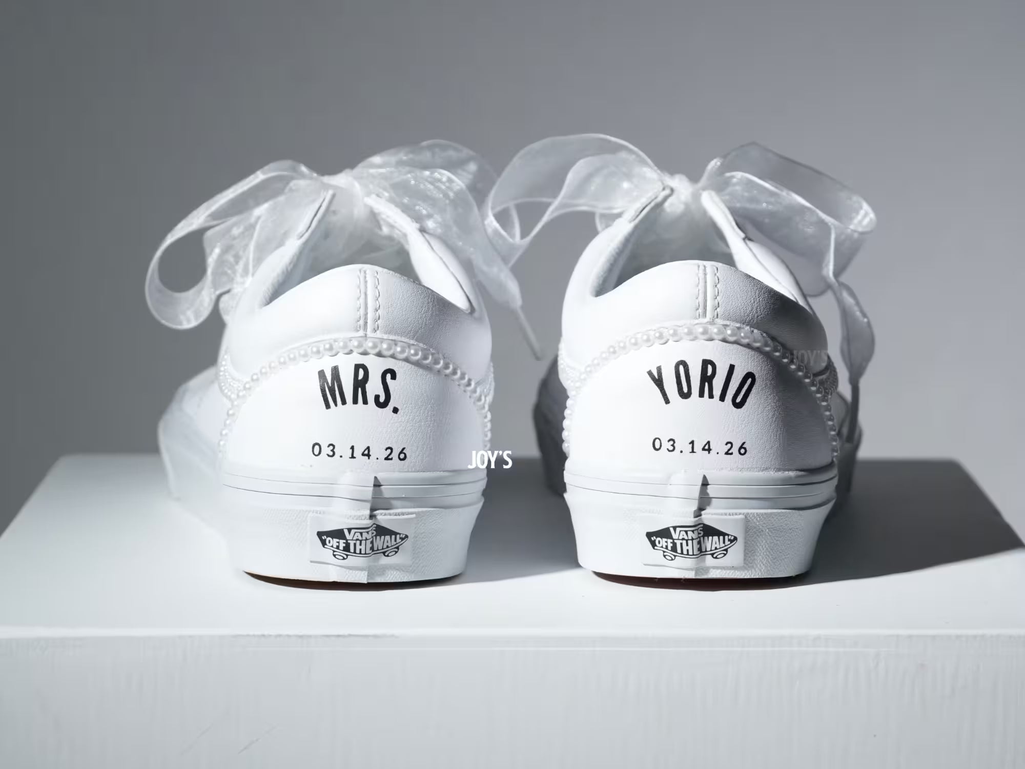Custom white Vans sneakers with pearl trim and “Mrs.” lettering on the heel, designed as bridal shoes.