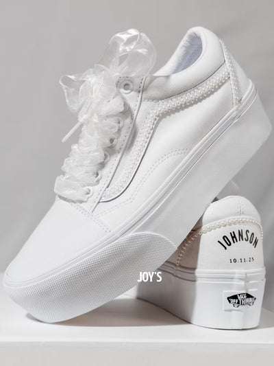 White platform Vans wedding sneakers with pearl trim, satin ribbon laces, and personalized “Mrs.” and last name with wedding date printed on the heels, shown in a rear view