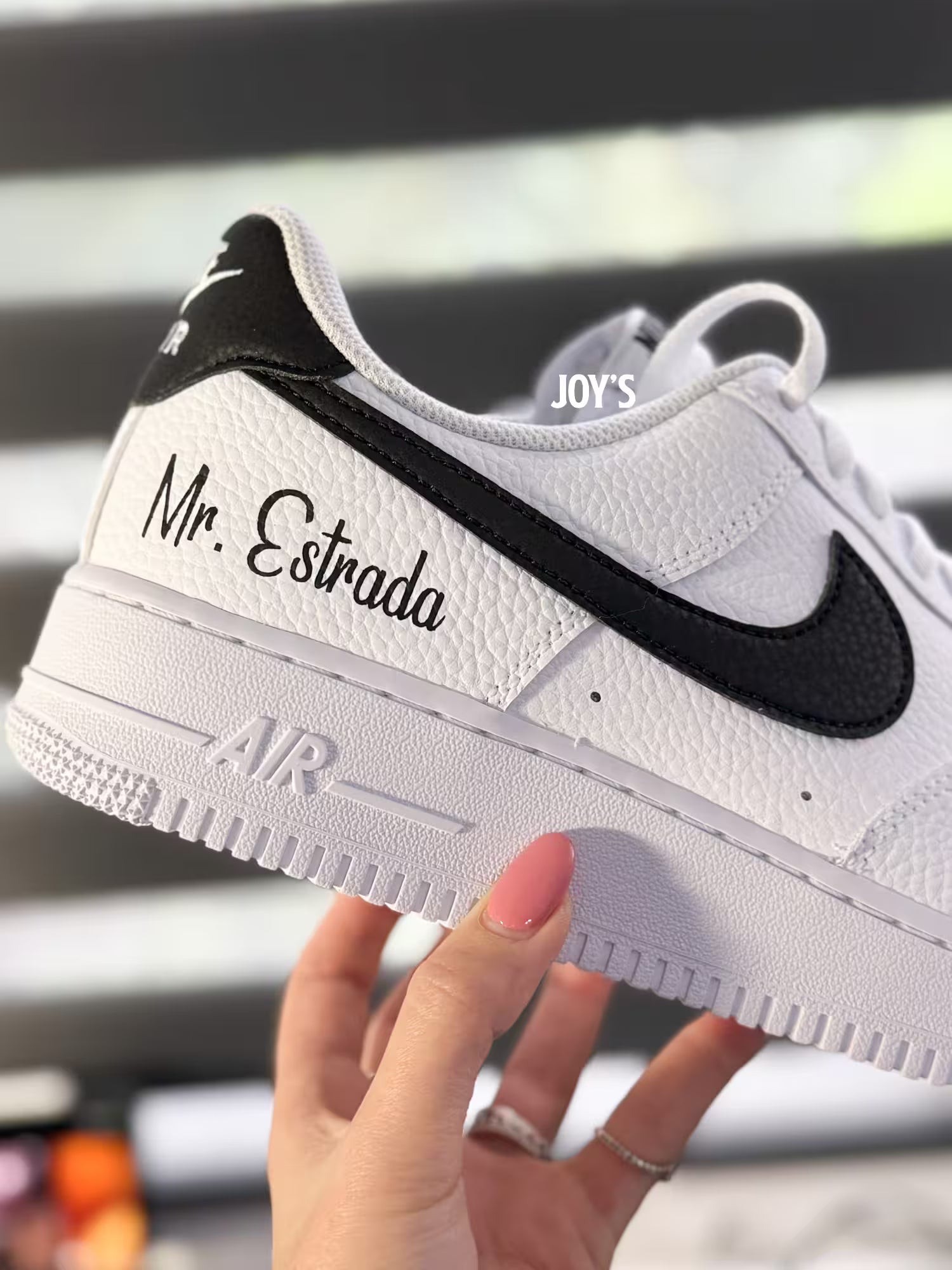 White custom Nike Air Force 1 sneakers with black swoosh, personalized last name and wedding date printed on the side, shown in a clean close-up view
