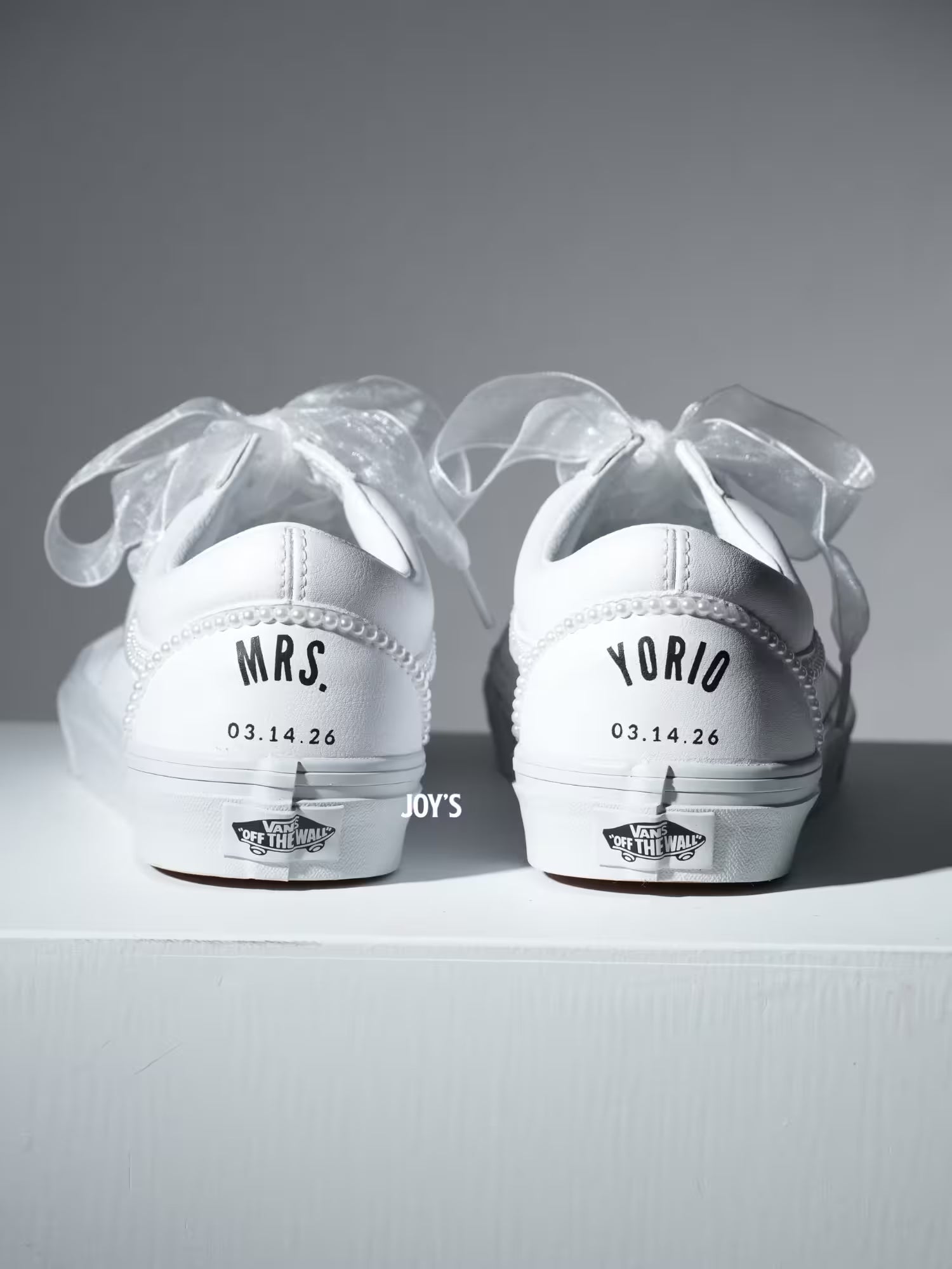 Custom white Vans sneakers with pearl trim and “Mrs.” lettering on the heel, designed as bridal shoes.