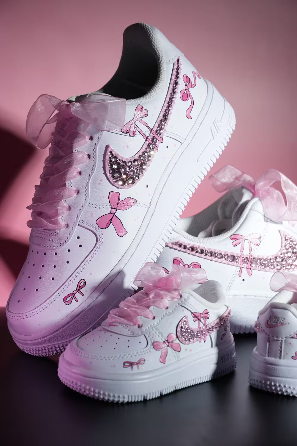 White custom sneakers with pink rhinestones, bows, and tulle laces for special occasions.