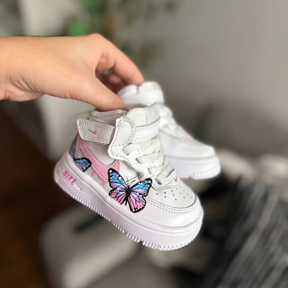 Custom hand-painted Nike Air Force 1 Mid baby sneakers with pastel butterfly artwork and pink details.