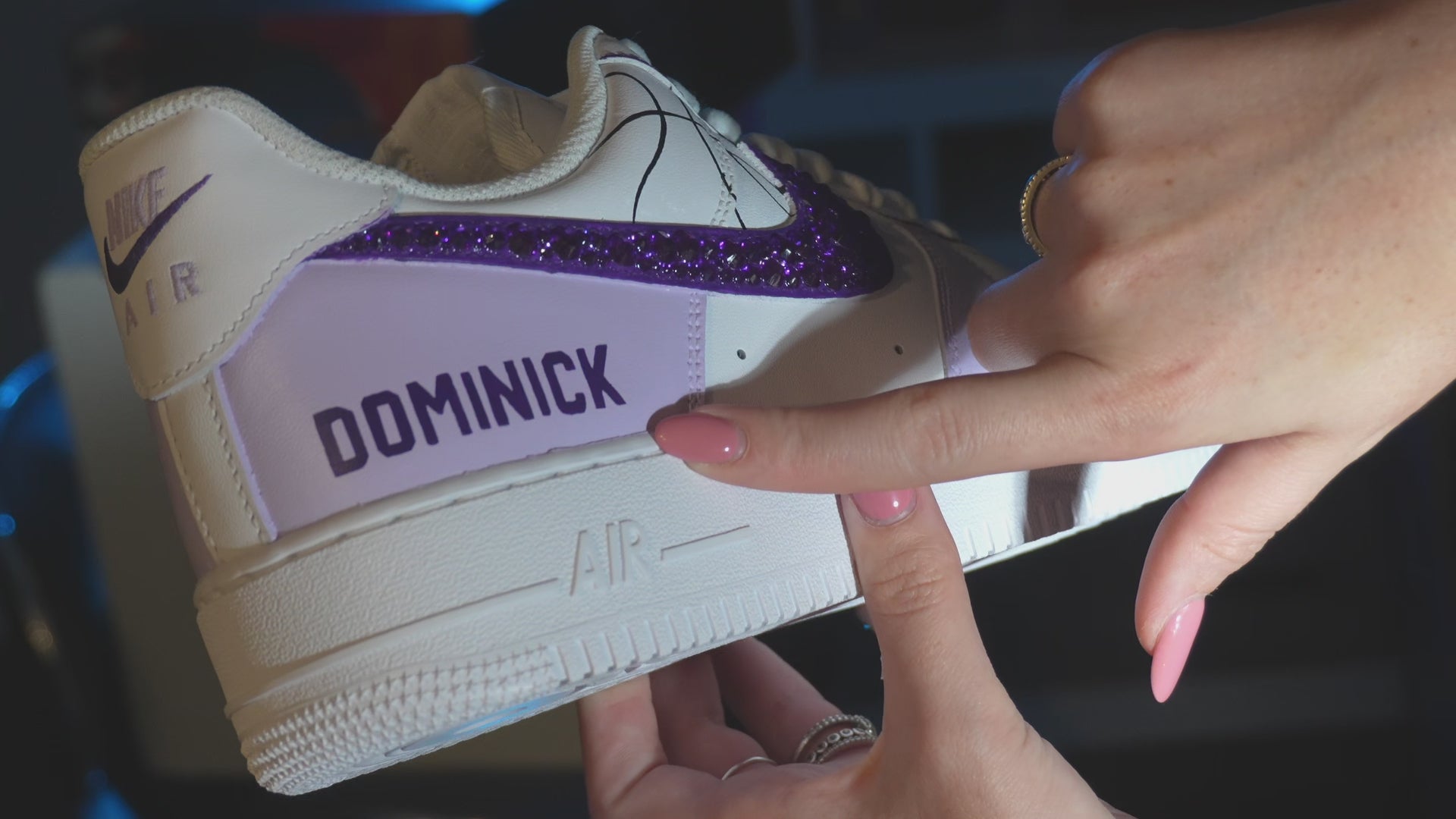 Load video: White and red sneakers with a brand logo held by a hand in an indoor setting.