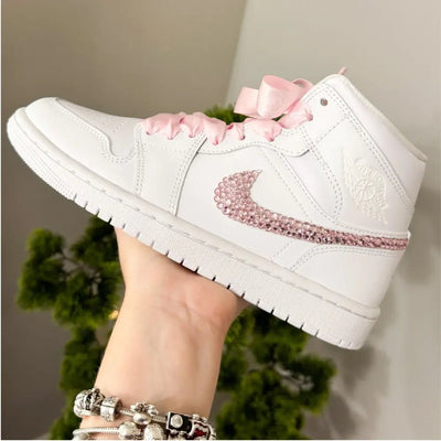 White Nike Air Force 1 Mid sneakers (standard sole, not platform), customized with a blush-pink crystal swoosh and matching pink ribbon laces. Clean, elegant finish with a soft bridal vibe, keeping the classic AF1 profile while adding subtle sparkle.