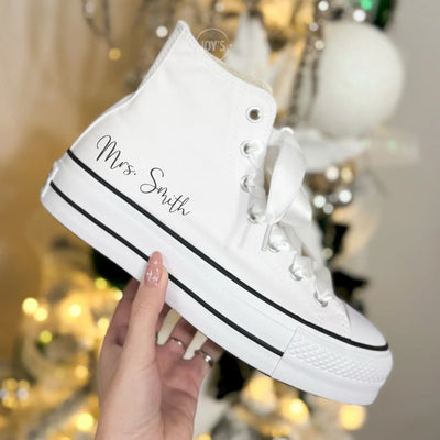 White platform Converse Chuck Taylor wedding sneakers and satin ribbon laces, shown in a hand-held close-up view