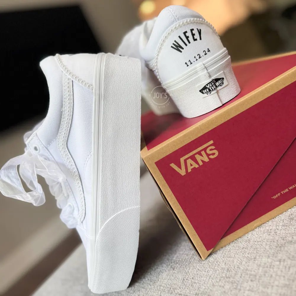 White platform Vans wedding sneakers with pearl trim, satin ribbon laces, and personalized “Mrs.” and last name with wedding date printed on the heels, shown in a rear view