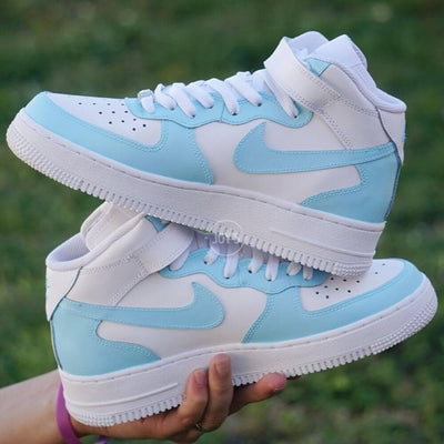 Custom Nike Air Force 1 mid sneakers with light blue and white color block design, featuring matching blue swoosh and white leather panels.