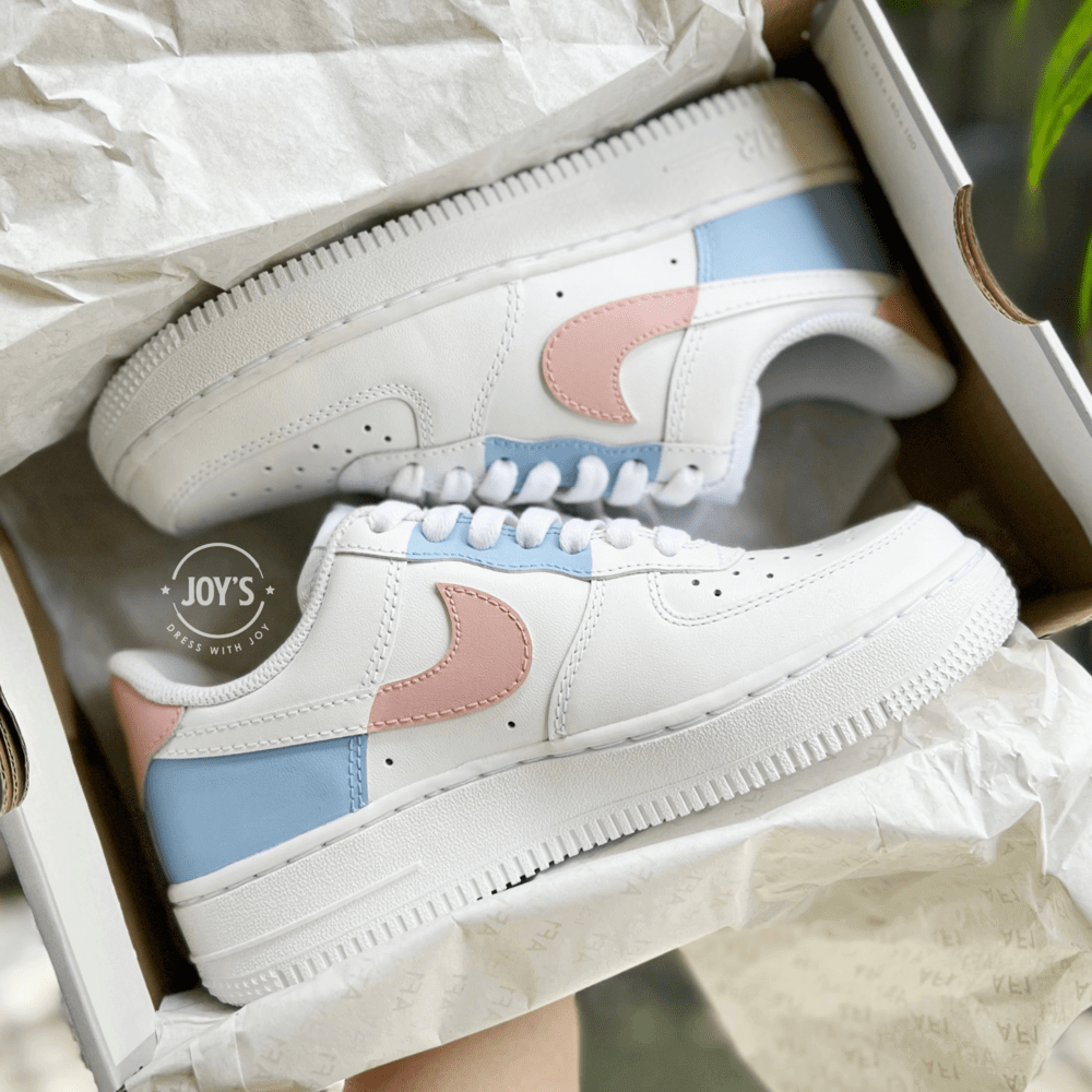 Pair of custom white Nike Air Force 1 sneakers in a shoebox, featuring pastel color-block swooshes in light blue and peach.